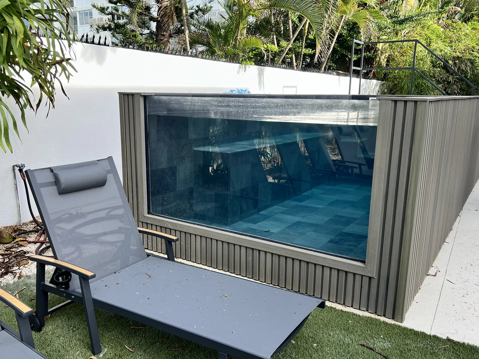 La piscina de pared de vidrio desde el jardín