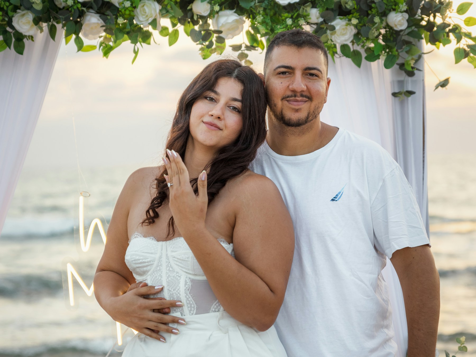 Couple beneath a floral wedding arch by the sea